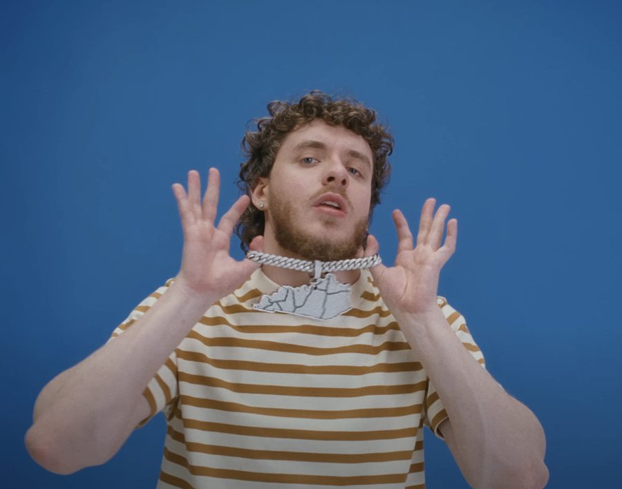 Jack Harlow in the Lovin On Me music video, hands raised, a chain collar locked around his neck
